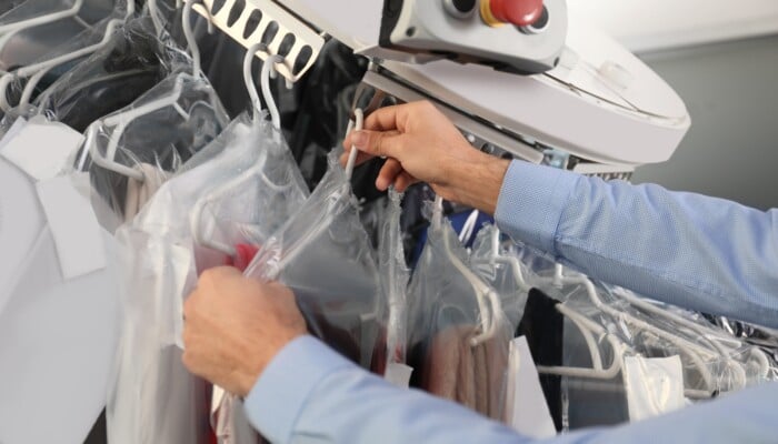 Male,Worker,Taking,Clothes,From,Garment,Conveyor,At,Dry cleaner's,,Closeup